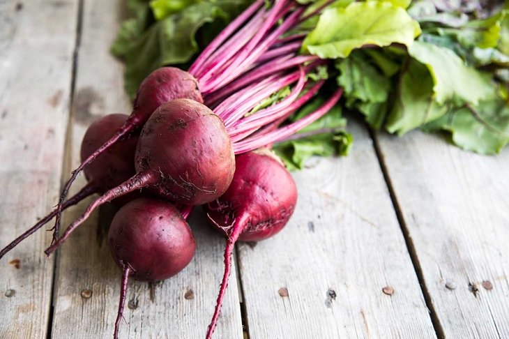 Red Beetroot with herbage green leaves on rustic background. Organic Beetroot.