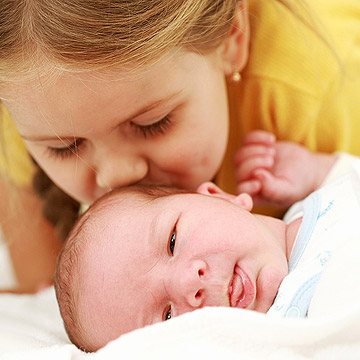 giving new baby a kiss