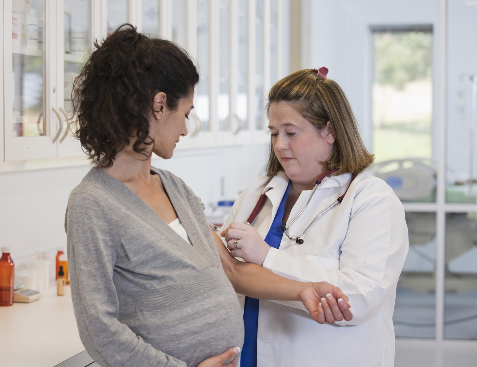 pregnant woman getting vaccine in doctors office